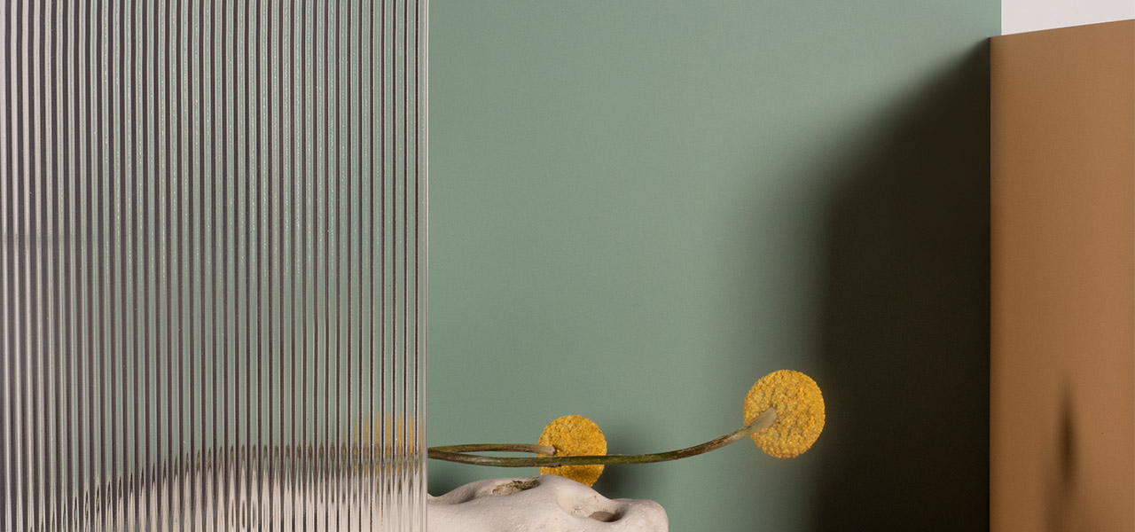 Moderne compositie met verschillende kleurenpanelen uit de Arpa Stock Collection, inclusief groen, bruin en transparant ribbelglas, gecombineerd met decoratieve bloemen.