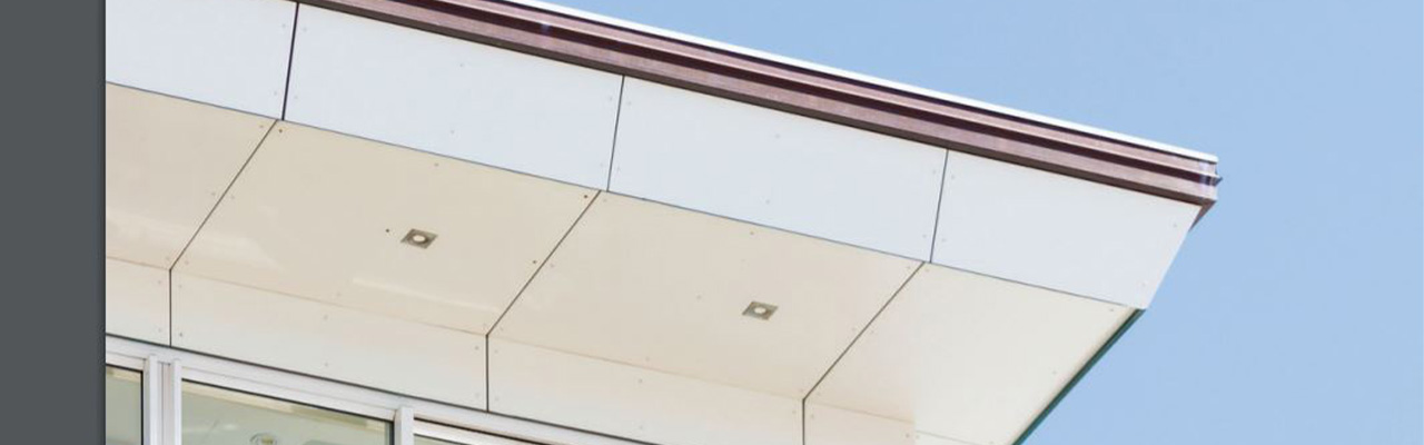  Een moderne gebouwgevel met compacte, weerbestendige platen die zijn aangebracht aan de onderkant van een dakoverhang, geschikt voor buitengebruik.