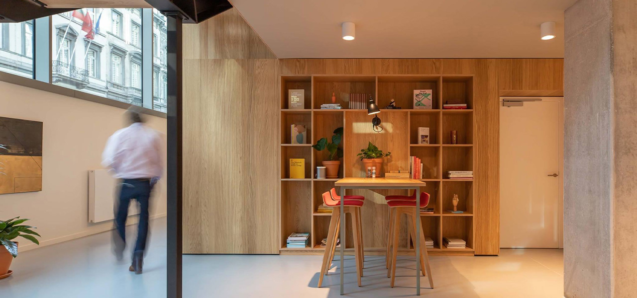 Modern interieur met Decospan houten wandpanelen, boekenplanken en een houten tafel met rode barkrukken.