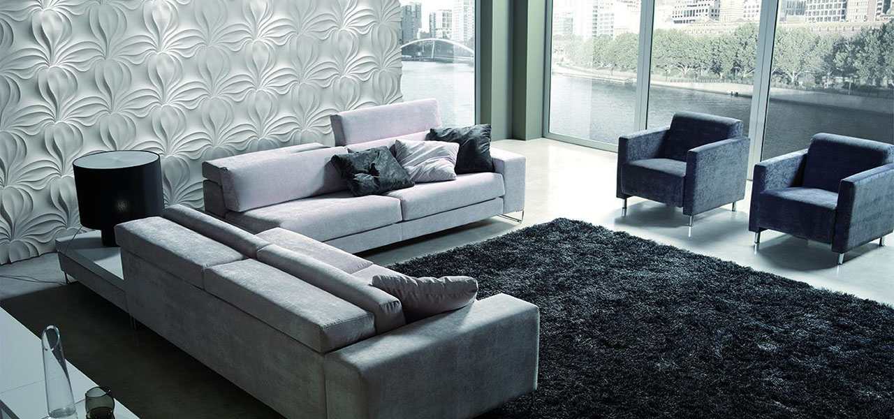 Een luxe woonkamer met een witte, decoratieve muur met een bladmotief, gecombineerd met een moderne, glazen wand met uitzicht op een rivier.