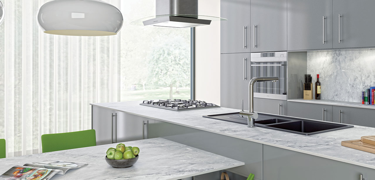 Moderne en lichte keuken met een lichtgrijze afwerking, een marmeren werkblad en strakke handgrepen. Grote ramen zorgen voor veel natuurlijk licht. Het eiland biedt een uitnodigende plek om te koken en te eten.
