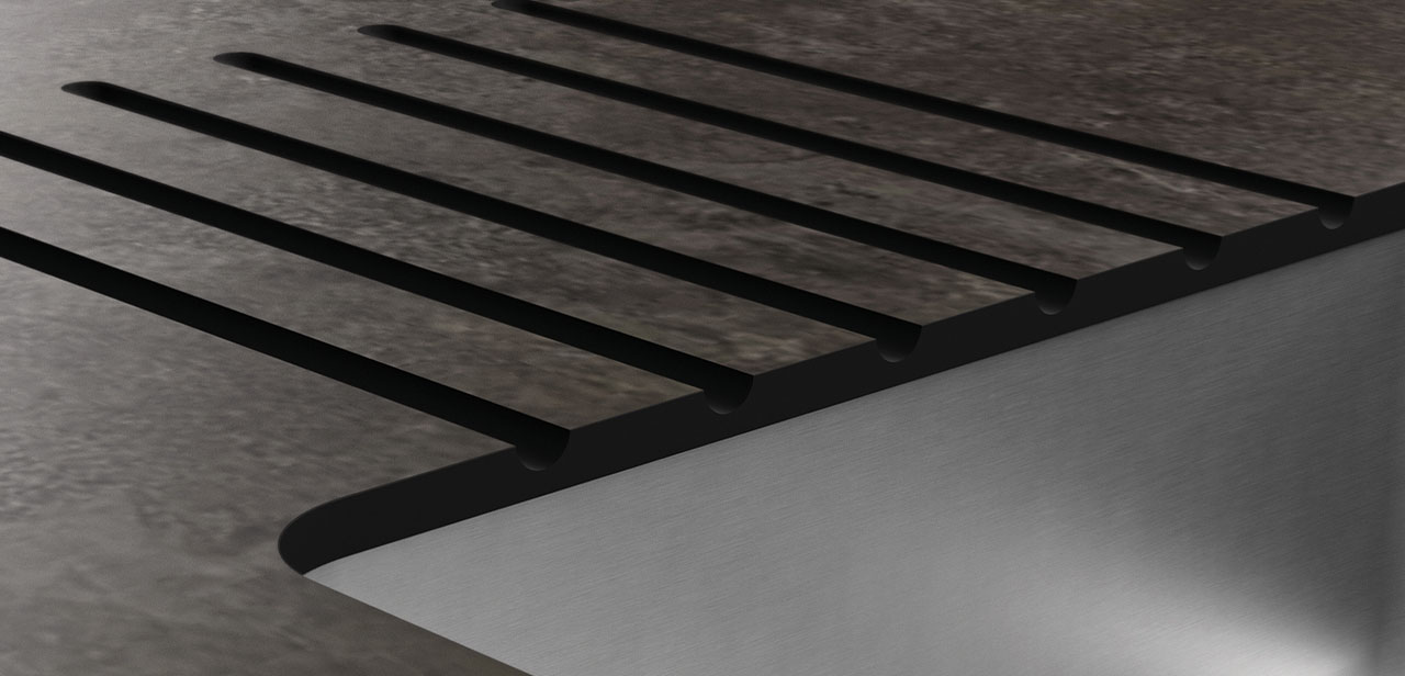 Close-up van een modern gootsteendesign met strak ingewerkte zwarte groeven in een donker werkblad met een steenachtige textuur. 