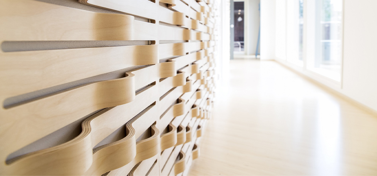 Een moderne, lichte ruimte met een decoratieve houten wand met golvende, gebogen houten elementen.