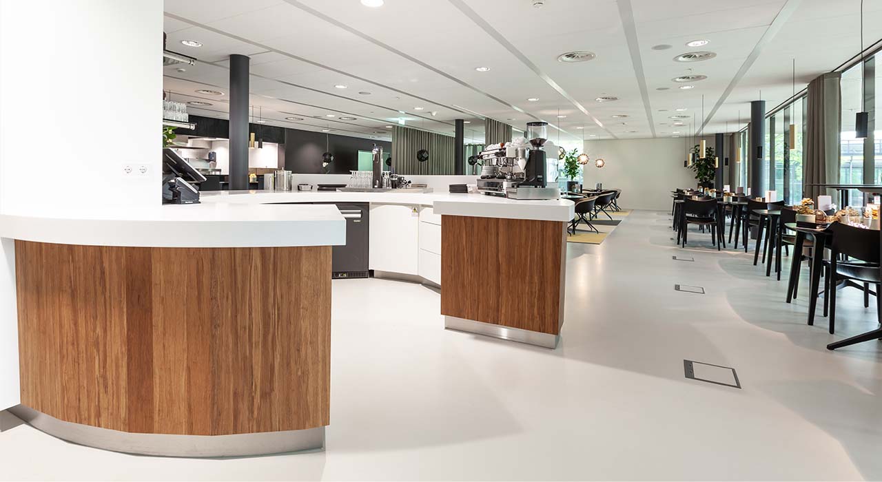 Ruime bar met koffiezetapparatuur en zitgelegenheden in een universiteitsrestaurant van de Technische Universiteit van Eindhoven.