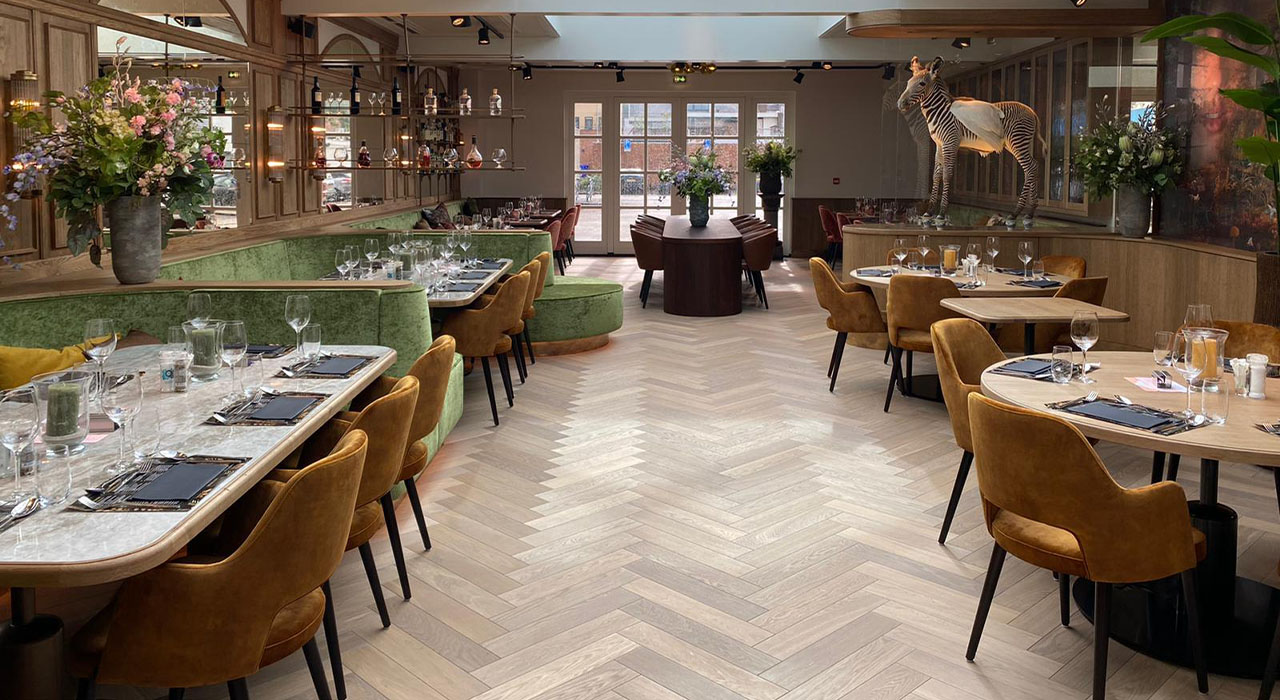 Bowling & Bistro Merlijn Oosterhout: Luxe restaurantinterieur met groene banken en marmeren tafels.