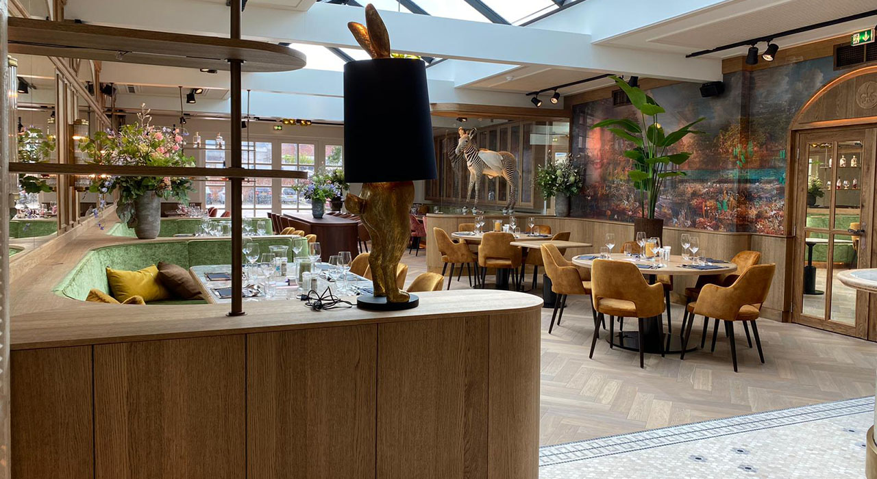 Bowling & Bistro Merlijn Oosterhout: Gezellige eethoek met fluwelen stoelen en houten details.
