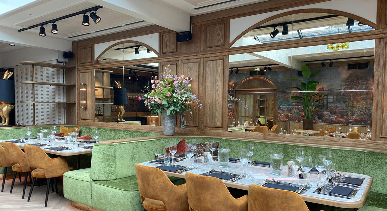 Bowling & Bistro Merlijn Oosterhout: Elegante zithoek met groene bank en bloemen op tafel.